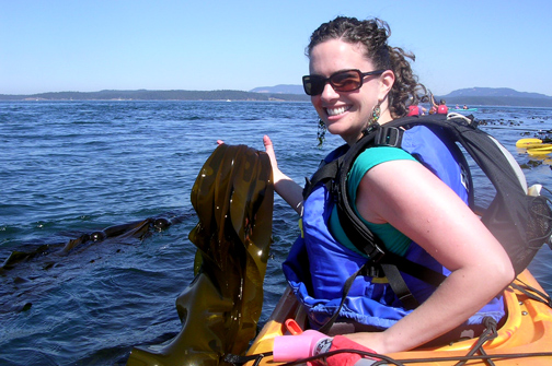 person holding seaweed on the water in a kayak