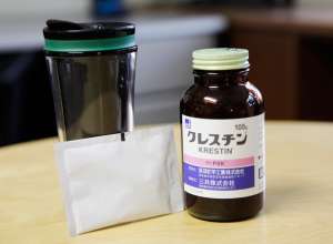 A bottle of medicine, by a glass of water, on a table