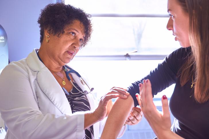 elbow being examined between doctor and patient