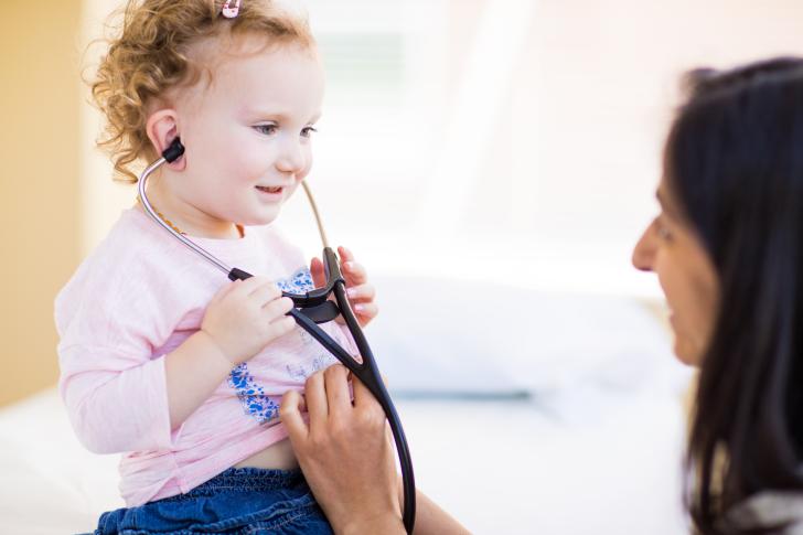 child holding stethoscope at doctors office
