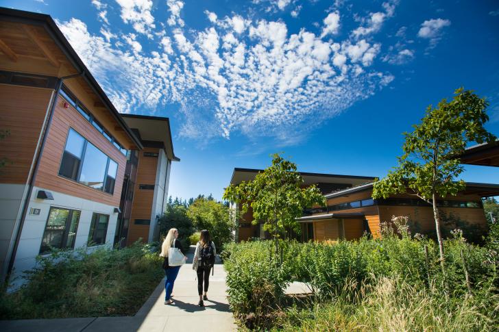 two students walking down sidewalk next to Bastyr Student Village