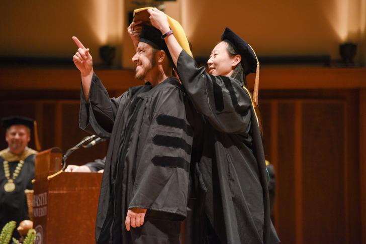 graduate pointing up in happiness