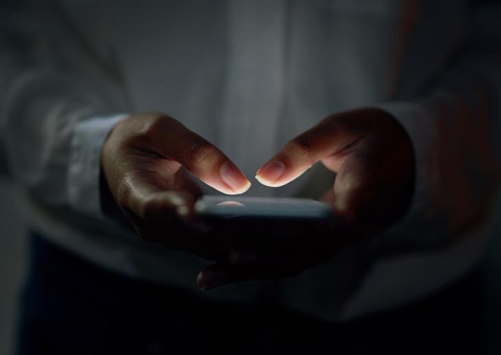 person typing on phone in dark