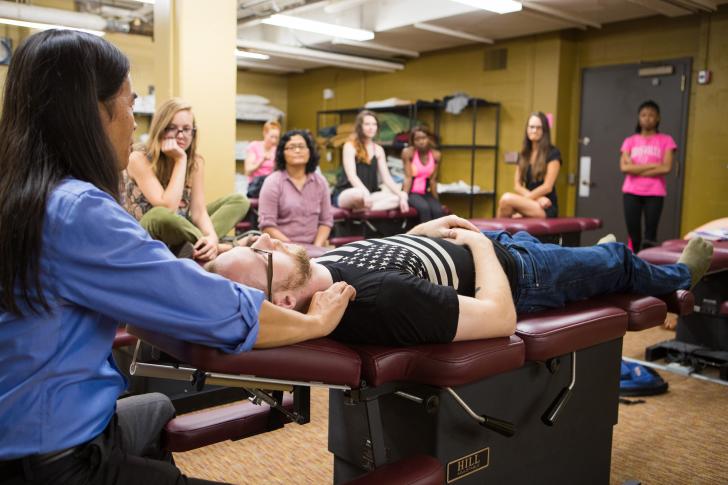 person teaching class with person on medical table