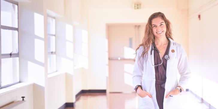 doctoral student smiling at camera with white coat on