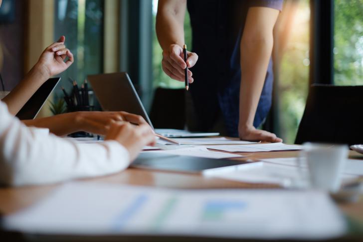 close up of two people's hands working at conference table