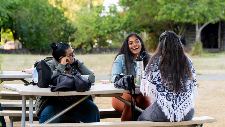 three students hanging out at table