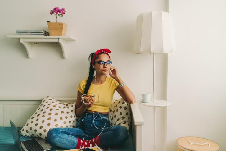 young adult eating almonds on couch