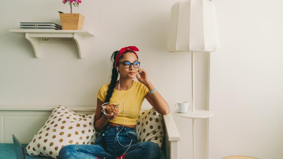 young adult eating almonds on couch